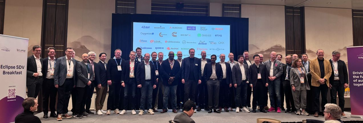 Large group of automotive open source leaders standing on a stage in front of a screen at CES.