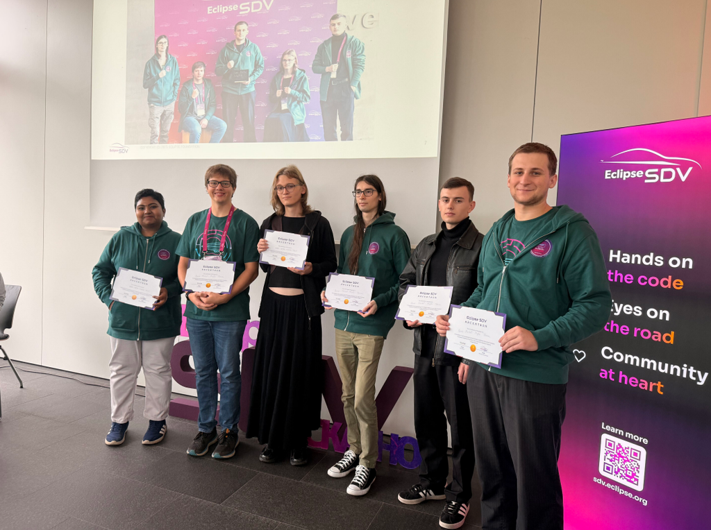 Group of six young people standing in a row facing the camera, all of them holding winners certificates in their hands